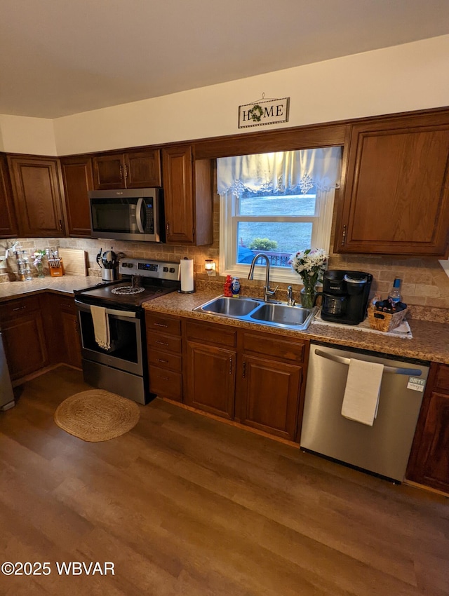 kitchen featuring stainless steel appliances, tasteful backsplash, a sink, and dark wood-style floors