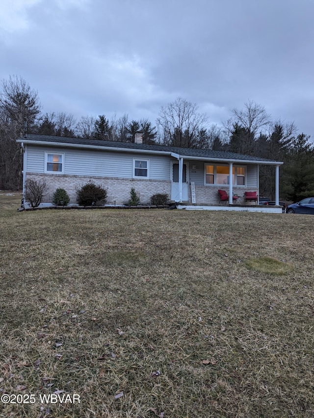 view of front of house with brick siding, a chimney, and a front yard