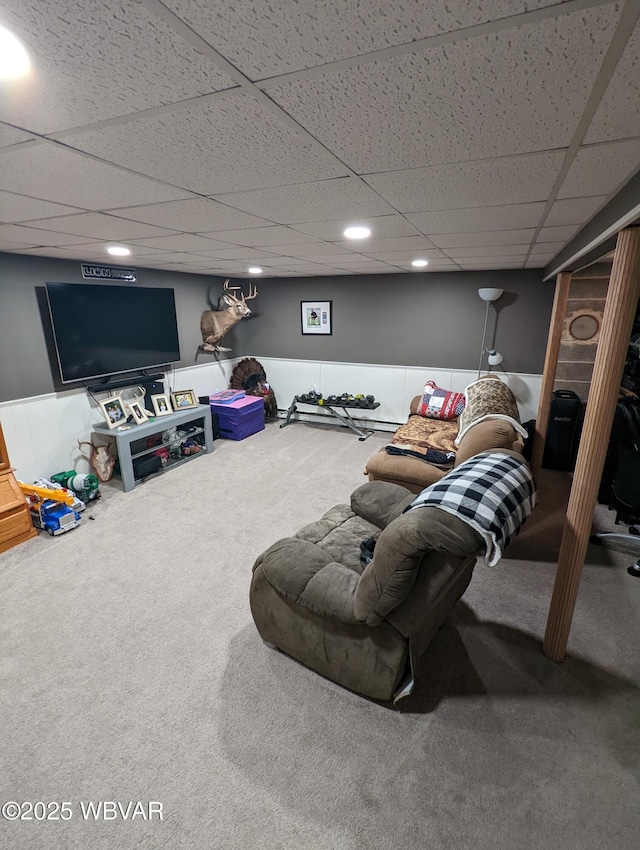 living room featuring a drop ceiling, carpet flooring, and wainscoting