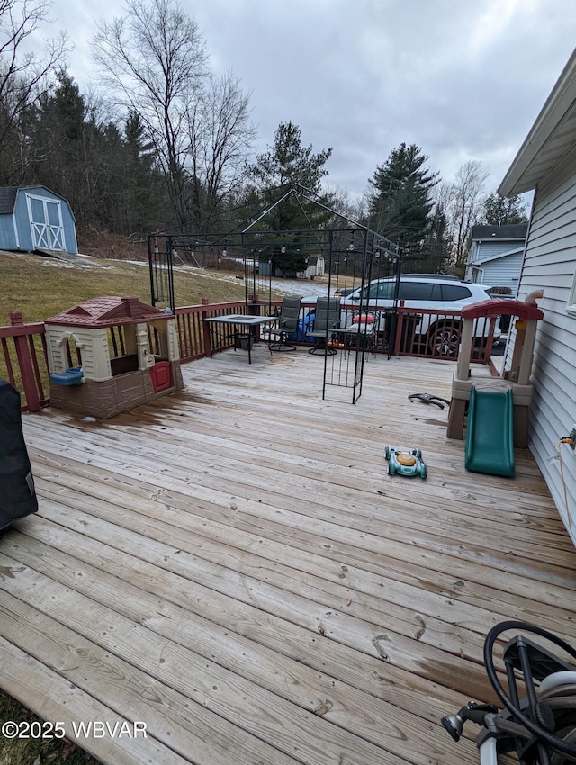 wooden terrace featuring an outdoor structure and a shed