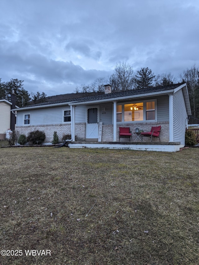 view of front of home featuring brick siding, a chimney, and a front yard