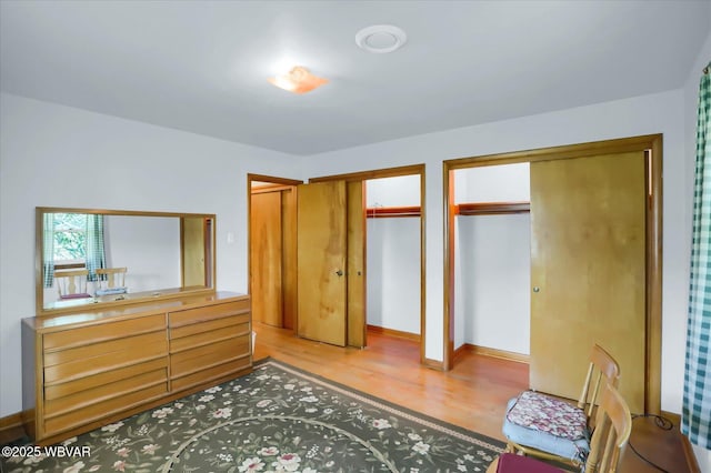 bedroom featuring hardwood / wood-style floors and two closets