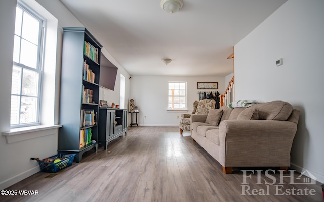 living room featuring baseboards, plenty of natural light, stairway, and wood finished floors