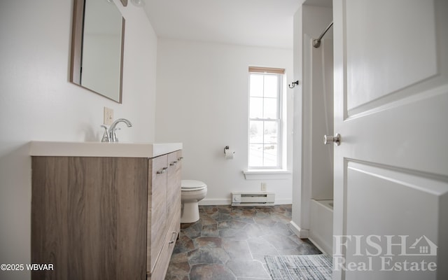 full bath featuring toilet, a baseboard heating unit, stone finish floor, vanity, and baseboards