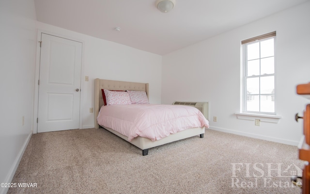 bedroom featuring light carpet, a wall unit AC, and baseboards