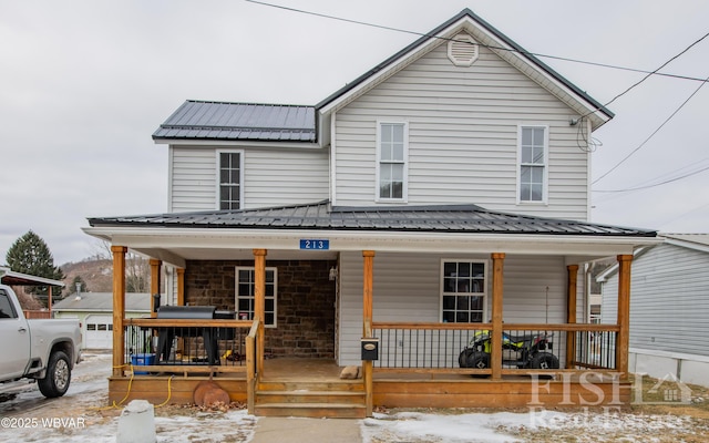 view of front of property featuring metal roof, stone siding, and a porch