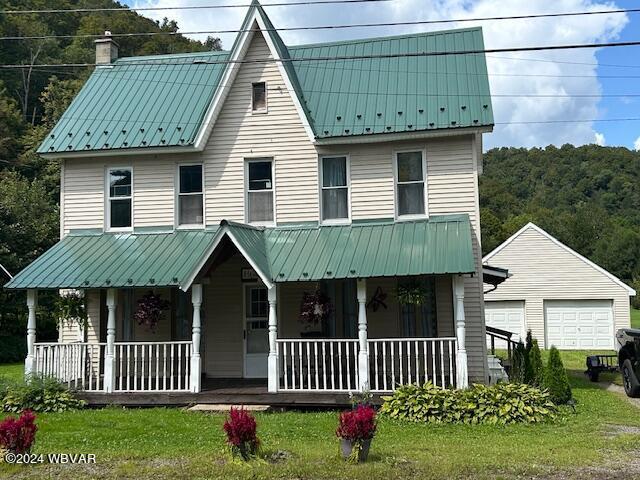 view of front facade with an outbuilding, a garage, a front lawn, and covered porch