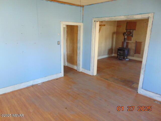 unfurnished room with a wood stove and hardwood / wood-style floors