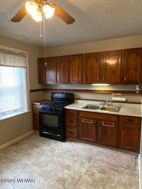 kitchen featuring black gas range, ceiling fan, and sink