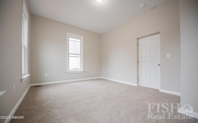 unfurnished room with carpet floors, visible vents, and baseboards