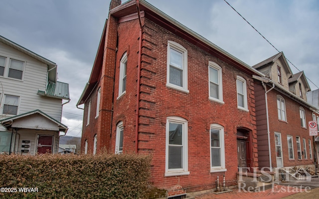 view of property exterior featuring a chimney and brick siding