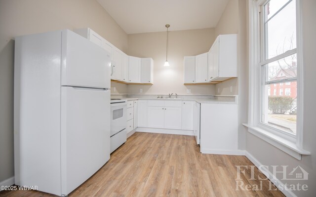 kitchen featuring white appliances, hanging light fixtures, light countertops, white cabinetry, and a sink