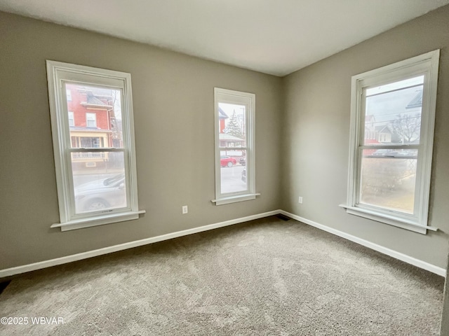 carpeted empty room featuring baseboards