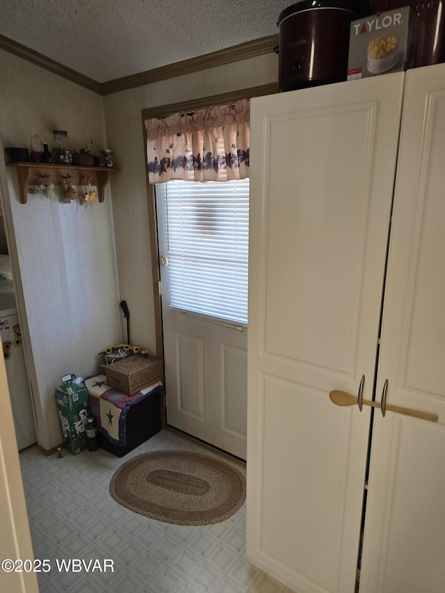 doorway to outside with ornamental molding and a textured ceiling