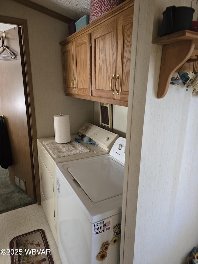 clothes washing area with a textured ceiling, cabinets, and washing machine and clothes dryer