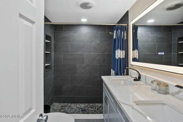 bathroom with a sink, recessed lighting, double vanity, and tiled shower
