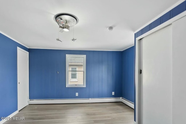 unfurnished bedroom with baseboards, ornamental molding, wood finished floors, and a closet