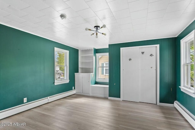 foyer entrance with a baseboard heating unit, a healthy amount of sunlight, and wood finished floors