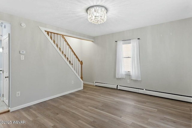 interior space featuring baseboards, wood finished floors, an inviting chandelier, and stairs