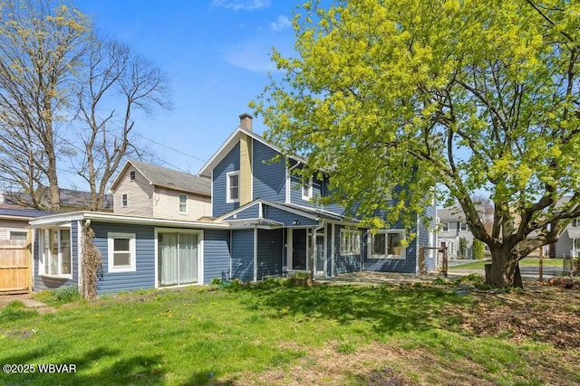 back of house with a chimney, fence, and a yard
