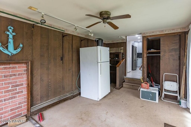 interior space featuring rail lighting, wood walls, and ceiling fan