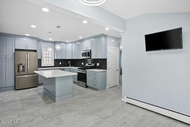 kitchen featuring baseboard heating, decorative backsplash, light countertops, appliances with stainless steel finishes, and a kitchen island