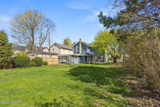 back of house with a lawn, a chimney, and fence