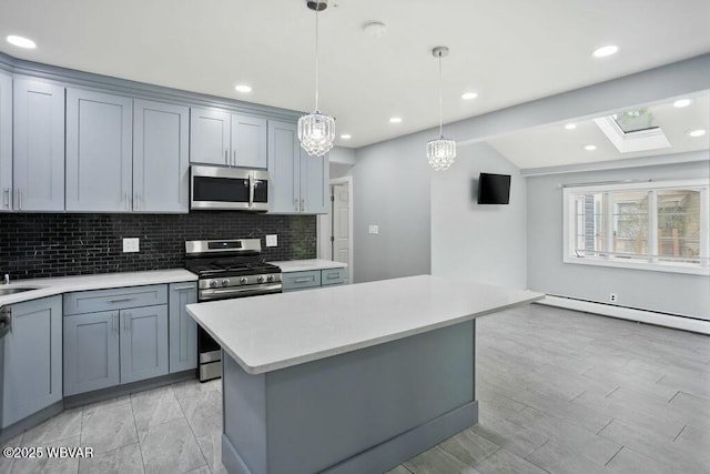 kitchen with stainless steel appliances, decorative backsplash, light countertops, a kitchen island, and hanging light fixtures