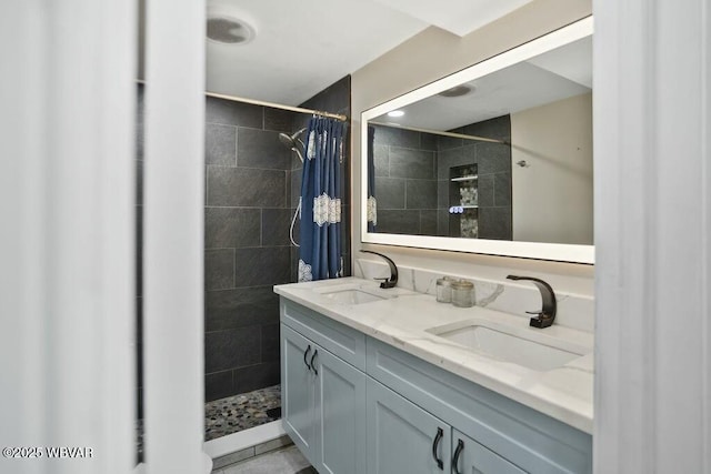 bathroom with a sink, double vanity, and tiled shower