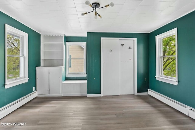 foyer with baseboard heating, crown molding, and wood finished floors