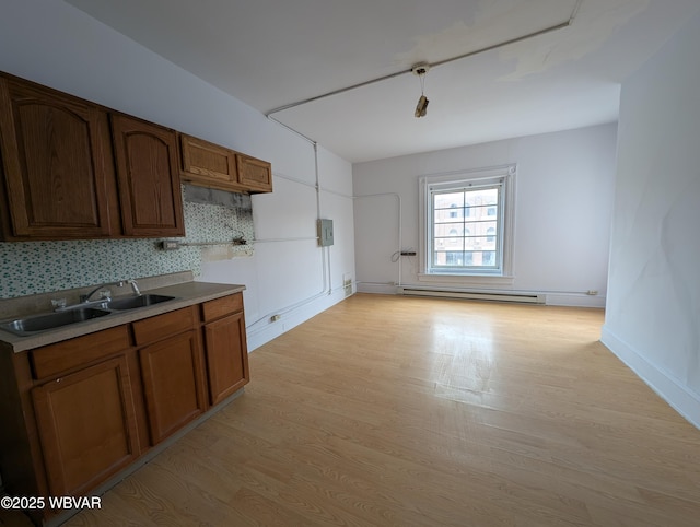 kitchen featuring a baseboard radiator, a sink, light countertops, decorative backsplash, and light wood finished floors