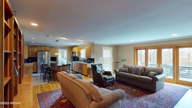 living room with french doors, light wood-type flooring, and ornamental molding