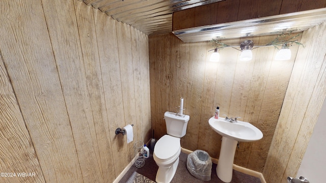 bathroom featuring sink, toilet, and wood walls