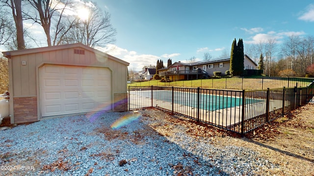 view of swimming pool featuring a yard, a garage, and an outdoor structure