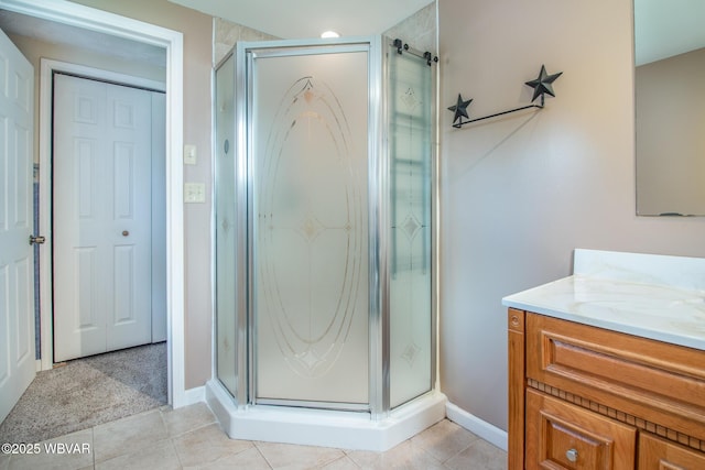 bathroom with a stall shower, tile patterned flooring, vanity, and baseboards