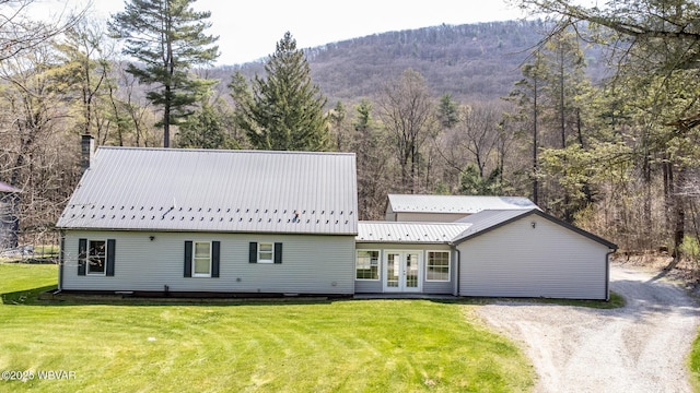 view of front of house featuring a chimney, a mountain view, french doors, and a front lawn