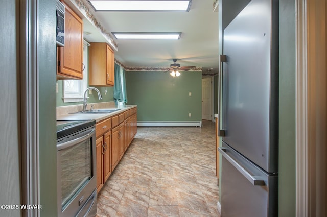 kitchen featuring a baseboard heating unit, a sink, ceiling fan, light countertops, and appliances with stainless steel finishes