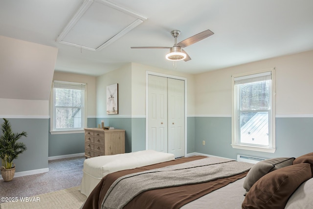 carpeted bedroom with baseboards, attic access, a ceiling fan, and a closet
