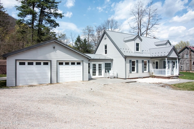 new england style home featuring metal roof, gravel driveway, a garage, and covered porch