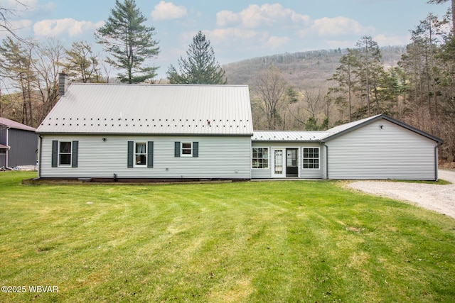 back of property featuring metal roof, a lawn, a mountain view, and a chimney