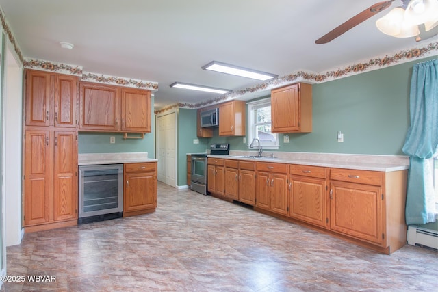 kitchen with appliances with stainless steel finishes, light countertops, ceiling fan, a sink, and wine cooler