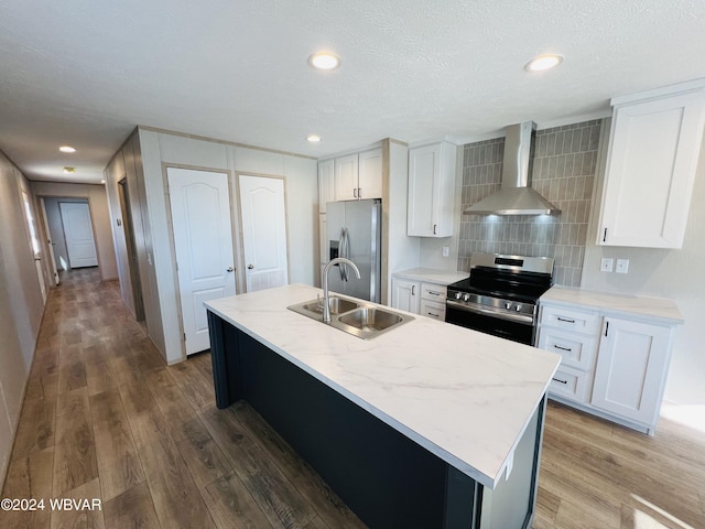 kitchen with appliances with stainless steel finishes, sink, a center island with sink, and wall chimney exhaust hood