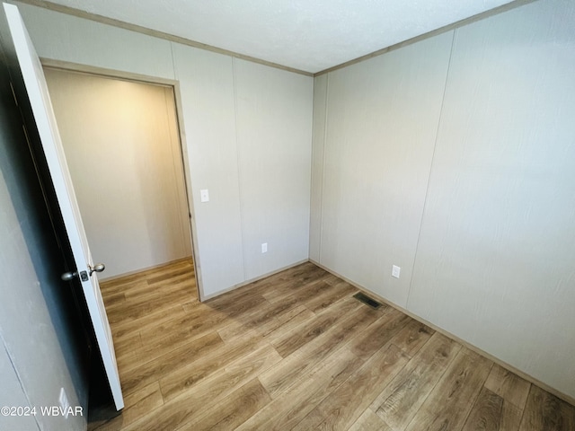 spare room featuring wood-type flooring and ornamental molding