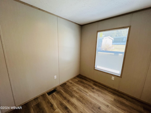 spare room featuring hardwood / wood-style floors and a textured ceiling