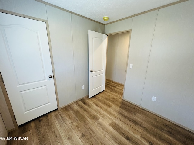 unfurnished bedroom featuring hardwood / wood-style floors, crown molding, and a textured ceiling