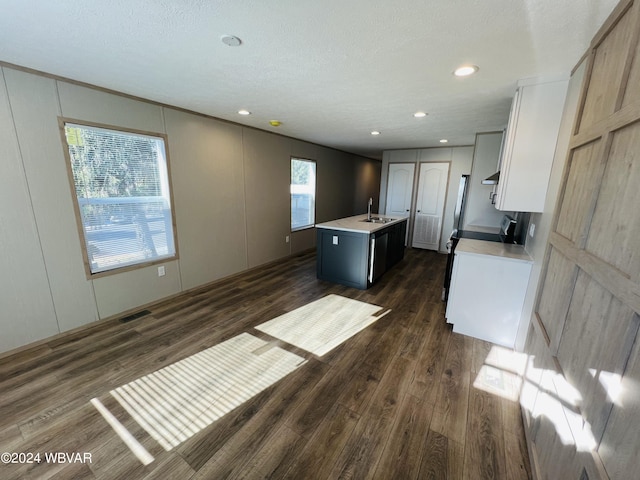 kitchen with sink, white cabinetry, a textured ceiling, dark hardwood / wood-style flooring, and a kitchen island with sink