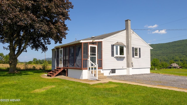 1945 Eagle Valley Rd, Beech Creek, PA 16822 - rear view of house featuring a sunroom, a lawn, and a chimney