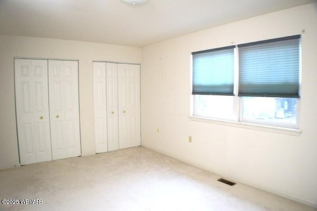 unfurnished bedroom with carpet floors and two closets