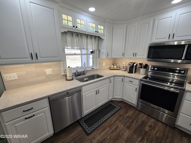 kitchen featuring dark wood finished floors, a sink, decorative backsplash, appliances with stainless steel finishes, and white cabinetry