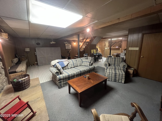 living area with stairway, wood walls, and a paneled ceiling